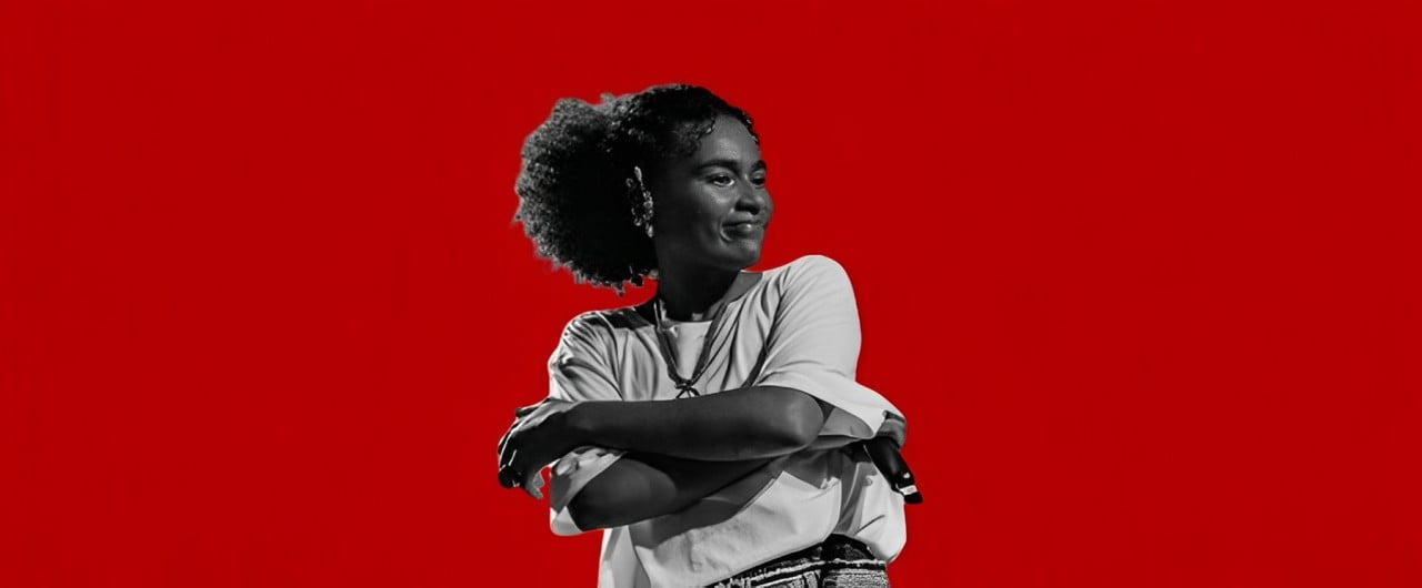 A cantora Anne Carol no centro da imagem em preto e branco. Em volta dela, o fundo em vermelho.